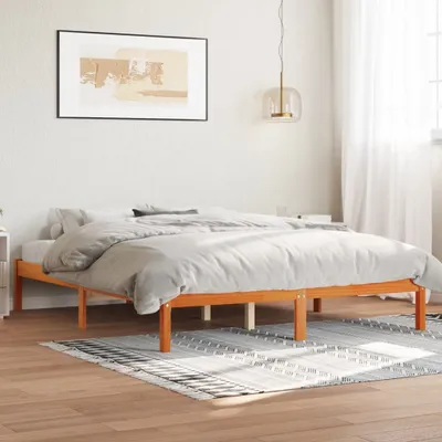 A wooden bed frame with bedding in a bedroom.