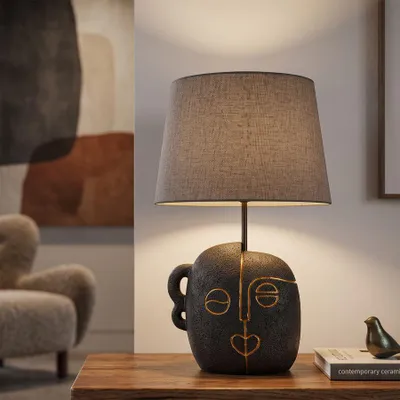 Immagine prodotto di Lampada da tavolo etnica, realizzata in resina, con paralume in tessuto, dimensioni 30,5x46 cm, colore marrone e oro, design Mauro Ferretti