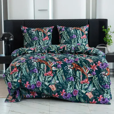 A bed with a duvet and pillows featuring a tropical floral and monkey pattern.