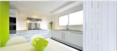 A modern, minimalist kitchen with white cabinets and a bright green accent wall.