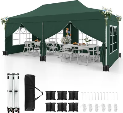 A green pop-up canopy tent set up with tables and chairs inside, suggesting an outdoor event or party setting. Accessories like sandbags and stakes are displayed below.