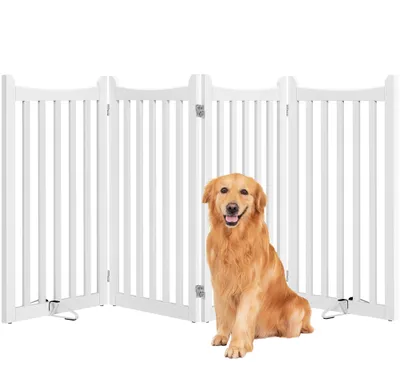 A golden retriever dog sits in front of a white wooden pet gate.