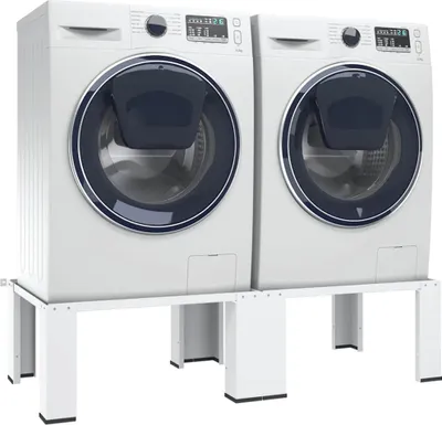Two white washing machines are placed on a white metal stand.