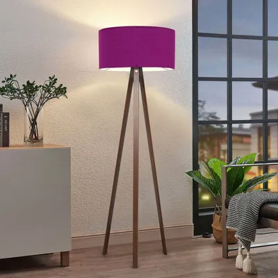 A purple floor lamp with a wooden tripod base is shown in a room with a window and a cabinet.
