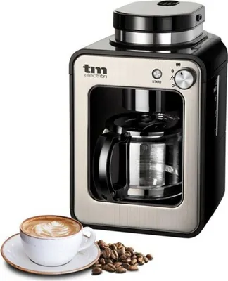 A coffee maker with a carafe and a cup of coffee with coffee beans.