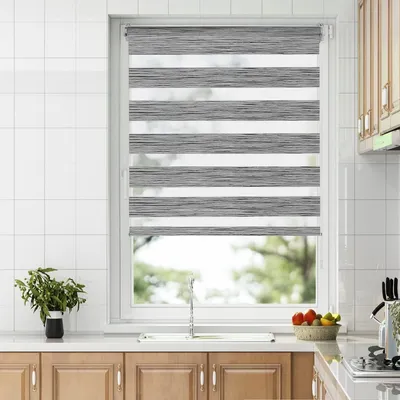 A kitchen window with a dual-layer roller blind, showing a sink and cabinets below.