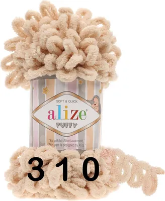 A ball of beige yarn with loops, sitting on top of its packaging.
