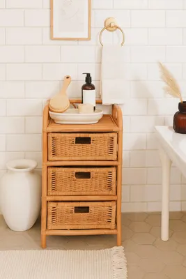 A rattan cabinet with three drawers stands in a bathroom.