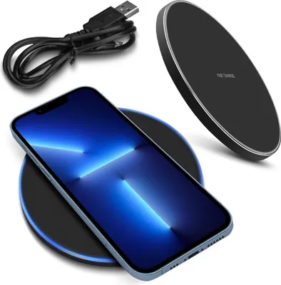 A smartphone is placed on a wireless charger, with a charging cable nearby.
