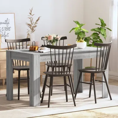 A dining table with chairs set in a room with plants and a framed picture.