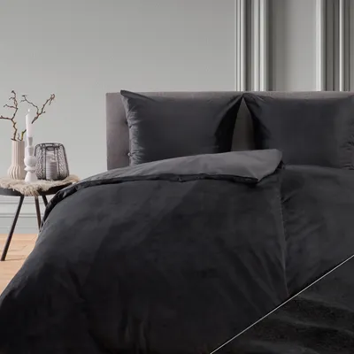 A close-up view of a black duvet cover and pillow on a bed.