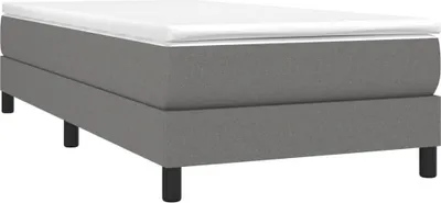 A studio shot of a gray boxspring bed frame with a white mattress on top, set against a white background.