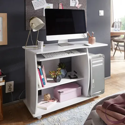 A white computer desk with a computer, keyboard, lamp, and decorative items.
