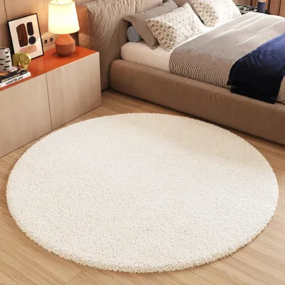 A bedroom scene with a bed, nightstand, and a round rug.