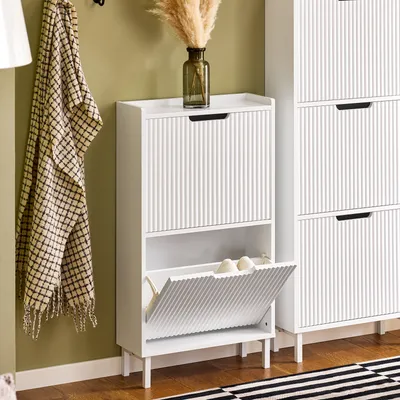 A white shoe cabinet with two flip-down compartments is shown in a room with a green wall and wooden floor.