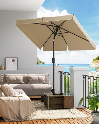 A balcony overlooking the ocean with outdoor furniture and a patio umbrella.