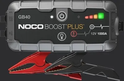 A NOCO GB40 Boost Plus jump starter with attached jumper cables, presented against a dark background.