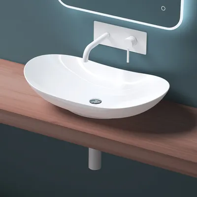 A white ceramic sink is mounted on a wooden shelf against a blue wall.
