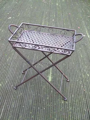 A metal folding table with a tray top sits on a wooden deck.
