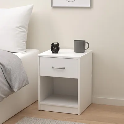 A white nightstand next to a bed.