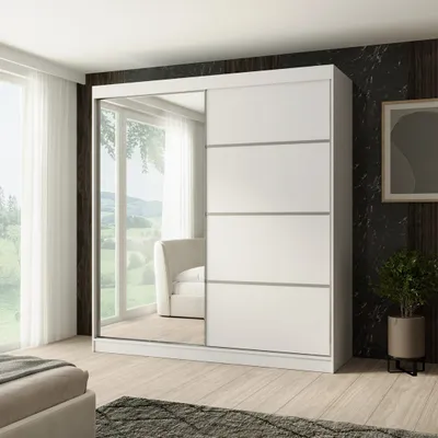 A white sliding door wardrobe with a mirrored door, placed in a bedroom setting with a window and a bed visible.