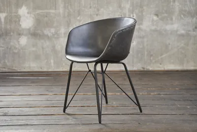 A dark gray armchair with a metal base is shown against a concrete wall and wooden floor.