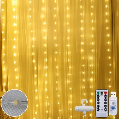 A curtain of warm white LED lights hanging against a yellow fabric background, with a remote control and USB adapter visible in the lower right corner.