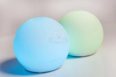 Two spherical diffusers, one blue and one green, on a light gray surface.