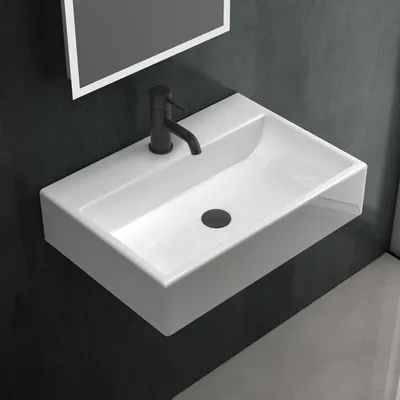 A white ceramic sink with a black faucet mounted on a dark gray wall.