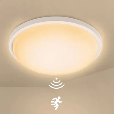A white, round LED ceiling light with a warm yellow glow, mounted on a light beige ceiling. Two white icons are displayed below the light: one representing motion detection (concentric arcs) and the other a running person.