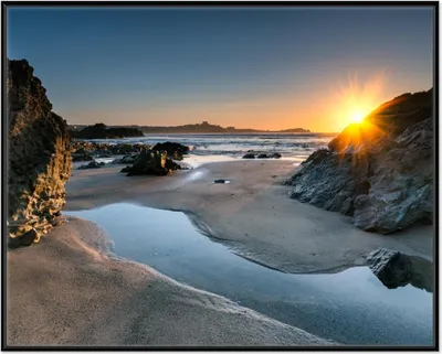 Produktbild von Wallario Wandbild Sonnenuntergang hinter einem Felsen am Strand, Größe: 40,30 x 50,30 cm, Poster mit schwarzem Aluminiumrahmen