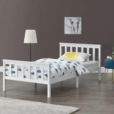 A white bed with bedding in a room with a dark gray wall and a blue stool.