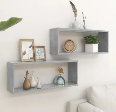 Two gray cube shelves mounted on a white wall, decorated with various items.