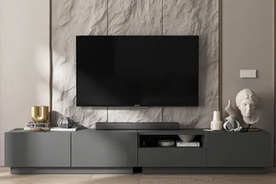 A modern living room setup featuring a TV stand and a large television mounted on a stone-effect wall.