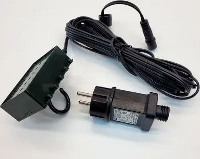 A black power adapter and a green distribution box with a hook are laid out on a white surface.