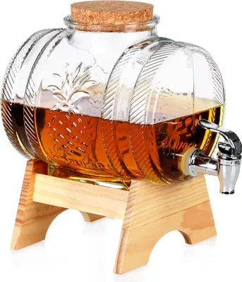 A glass beverage dispenser with a spigot, filled with a brown liquid, resting on a wooden stand.