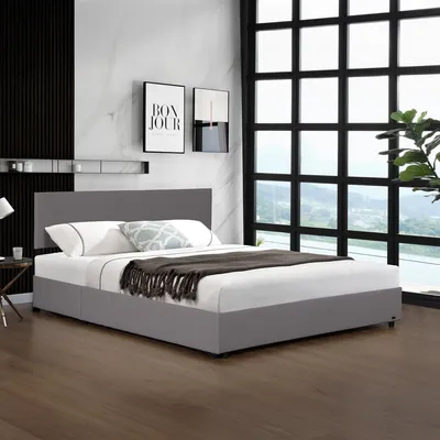 A modern bedroom with a gray upholstered bed frame and headboard, set against a marble-patterned wall and a large window with a grid pattern.