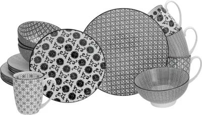 A collection of black and white patterned ceramic dishes and mugs arranged on a white background.