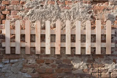A small wooden fence is attached to a weathered brick wall.