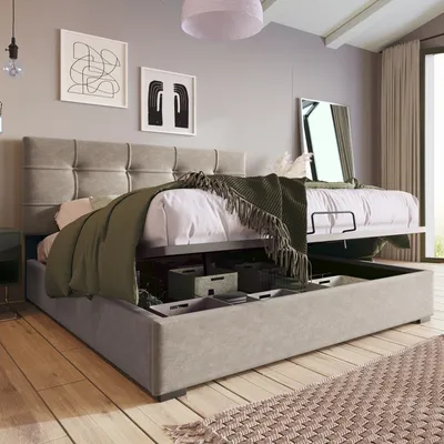 A bedroom with a bed that has storage underneath, decorated with artwork and a mirror.