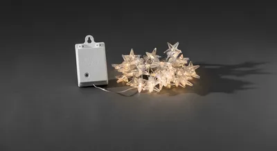 A battery-powered LED string light with star-shaped bulbs and a battery pack are placed on a dark gray surface.