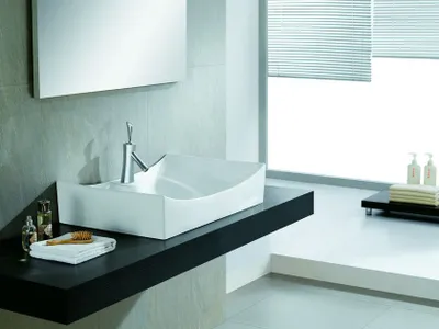 A modern bathroom sink on a dark countertop.