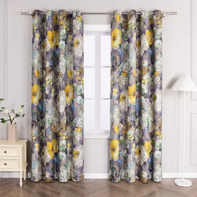 A pair of floral patterned curtains hanging in front of a window, with a bedside table and lamp visible.