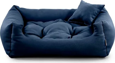 A dark blue dog bed with a small pillow on a white background.