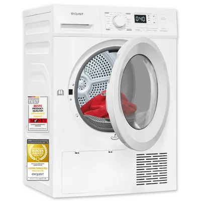 A white Exquisit heat pump dryer with its door open, showing a red towel inside. There are several award badges on the left side of the dryer.
