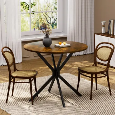 A round dining table with two chairs in a room with a window and curtains.