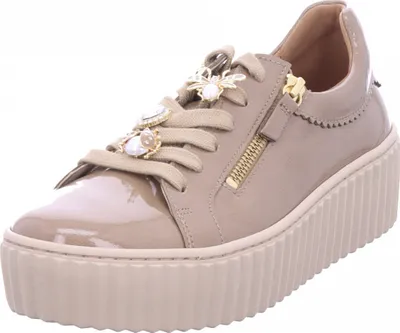 A single beige women's sneaker with a platform sole and decorative embellishments.
