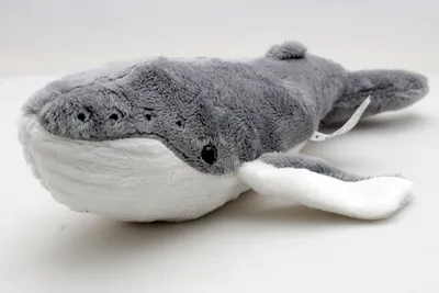 A plush toy whale lying on a white surface.