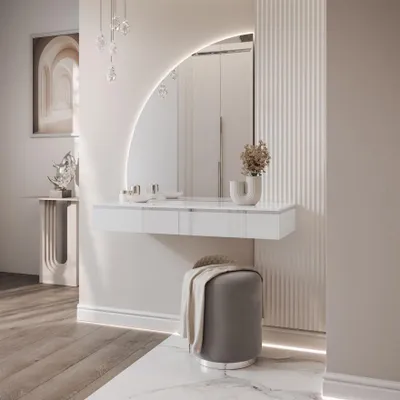 A modern vanity table with a large arched mirror and a grey stool in a well-lit room.