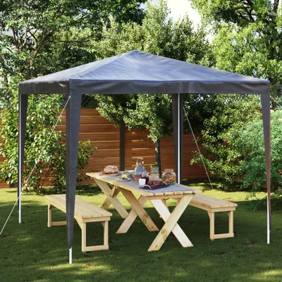 A party tent set up in a garden with a picnic table and benches.
